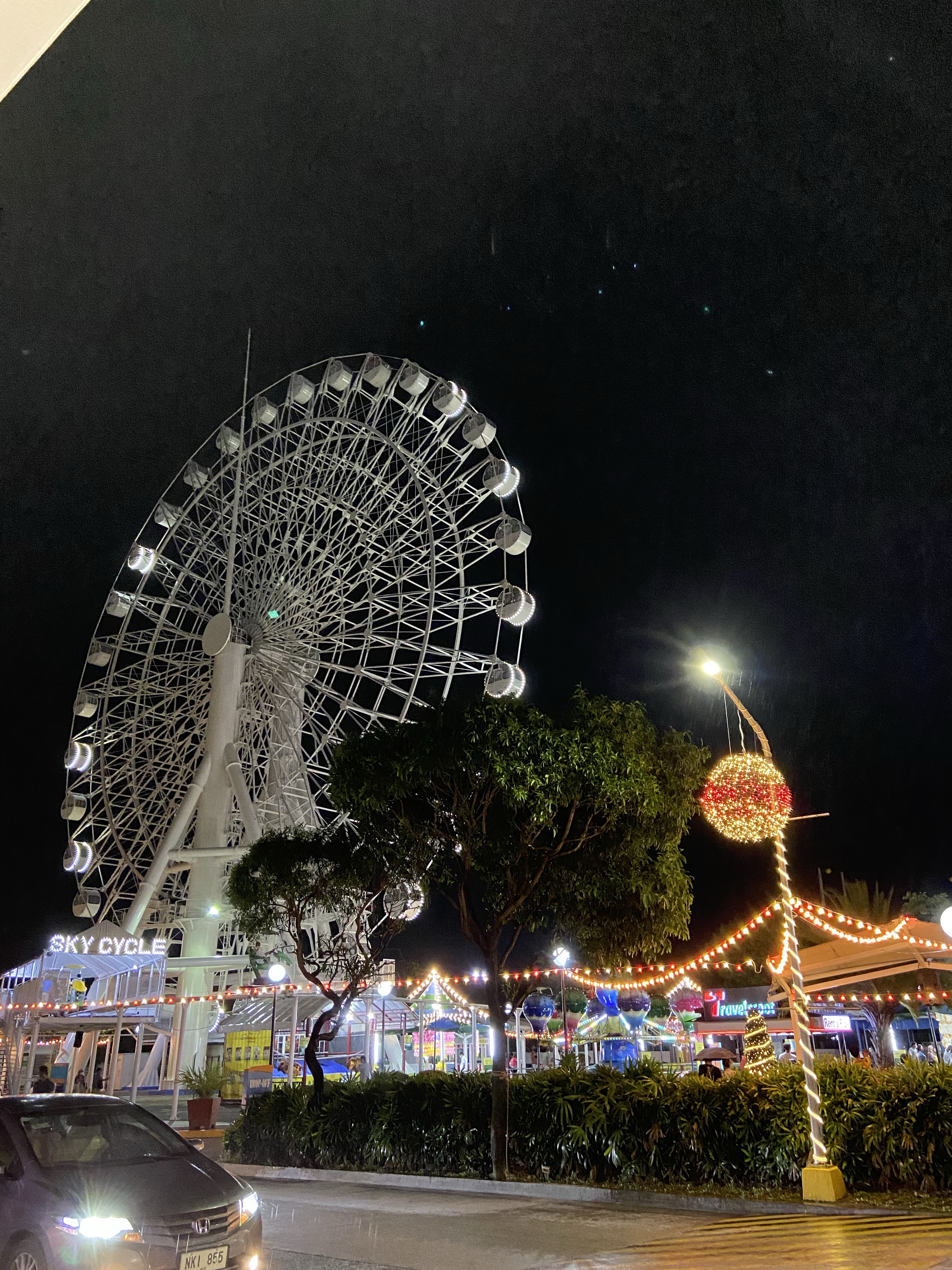A brightly lit Ferris wheel and colourful night-time attractions