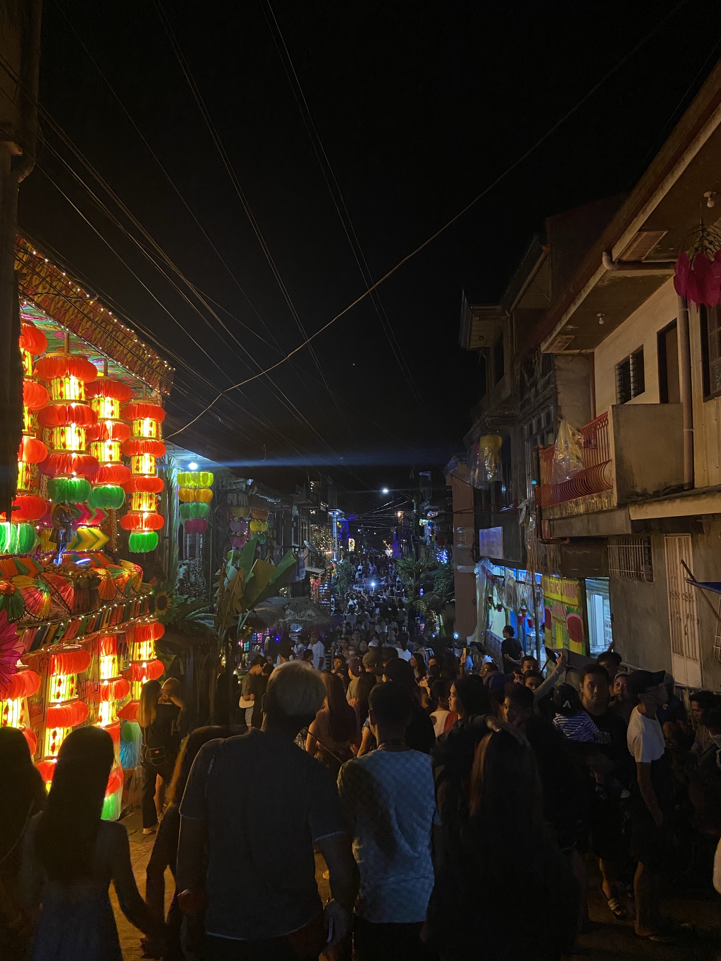 A lively night market street filled with colourful lanterns and lights